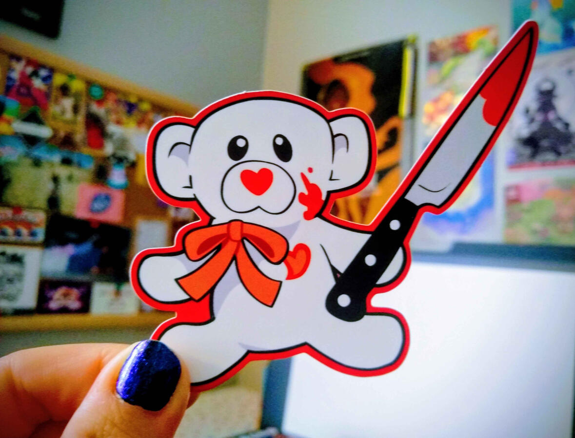 Sticker design of a white Valentine's teddy bear holding a bloody steak knife, with blood on its cheek.
